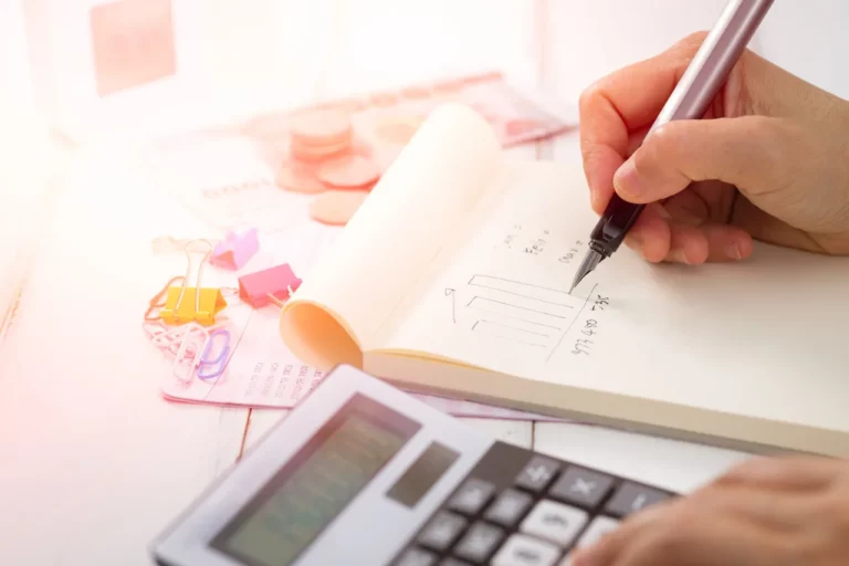 calculator and notepad hand with pen is writing on notepad