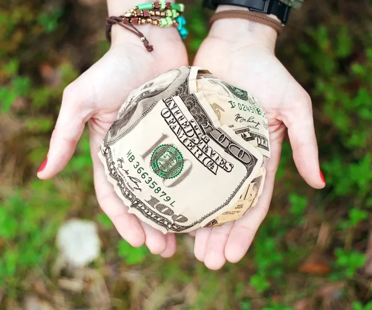 pair of hands holding a ball of cash