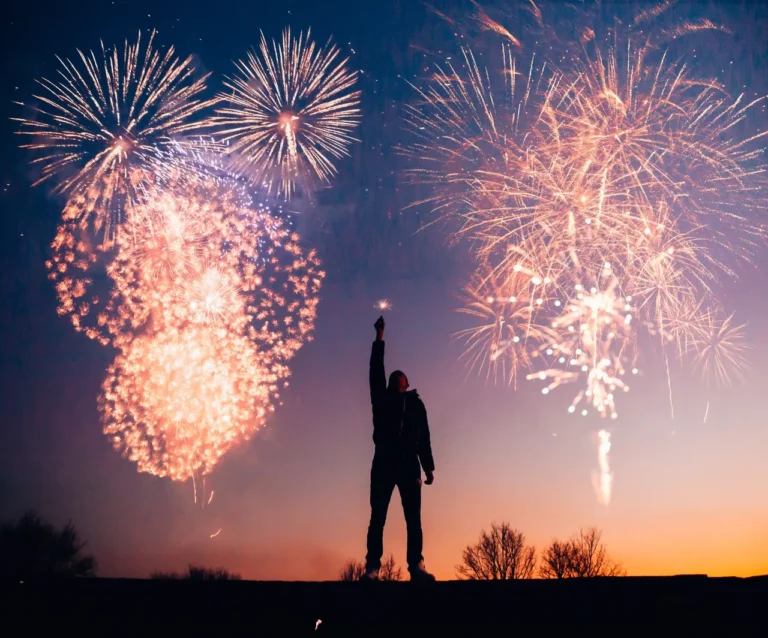 fireworks at sunset silouette of person holding a candle