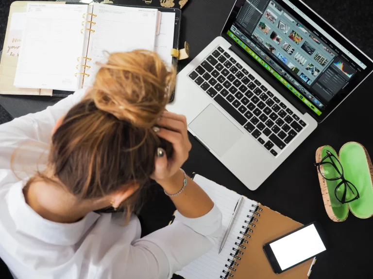 woman setting at computer desk holding her head